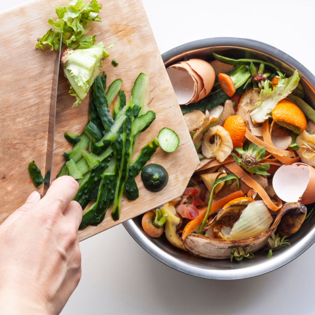 a hand cutting vegetables on a cutting board next to a bowl of food