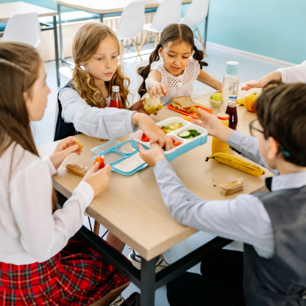 a group of kids sitting at a table eating food